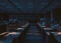 Empty crypto exchange office desks with market chart monitors representing Coinbase restructuring