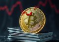 Bitcoin coin with a falling red chart and credit cards on a dark background