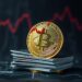 Bitcoin coin with a falling red chart and credit cards on a dark background